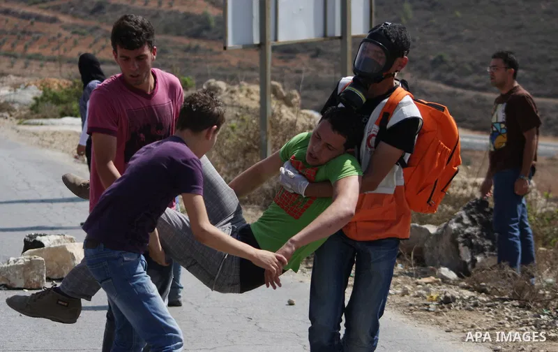 Palestinian protesters carry a wounded comrade during cashes in the West Bank village of Nabi Saleh between locals and Israeli soldiers after a march organized by the village's residents to protest the expansion of the n...