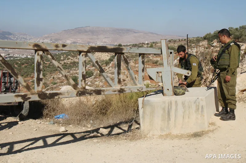 Israeli soldiers stand guard at a barrier erected on Palestinian land to protect nearby Jewish settlements in the occupied West Bank, as Palestinian farmers cross to harvest their olive groves just outside the Palestinia...