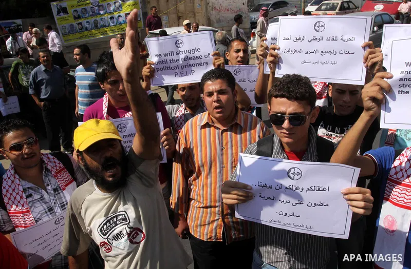 Families of Palestinian prisoners held in Israeli jails shout slogans while holding banners during a protest outside the International Committee of the Red Cross (ICRC) offices in Gaza City on October 3, 2011 in support...
