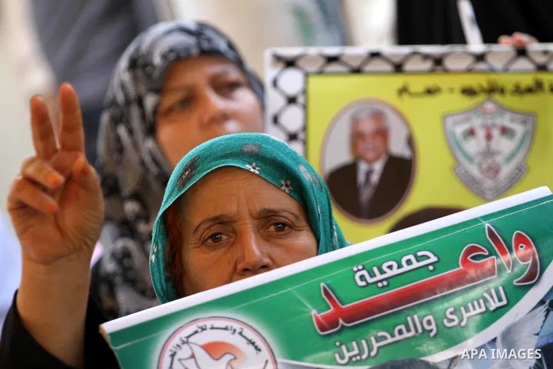 A Palestinian woman holds picture of her relatives who are imprisoned in an Israeli jail during a protest at the Red Cross headquarters in Gaza City on October 3, 2011 in support of prisoners on hunger strike. Photo by M...