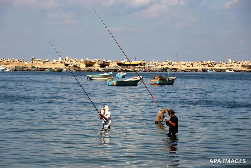 Palestinian men fish as others participate in a press conference at the Gaza Seaport on Oct. 5, 2011 against the violations of Israeli forces against the Palestinian fishermen in the Mediterranean Sea.. Photo by Majdi Fa...