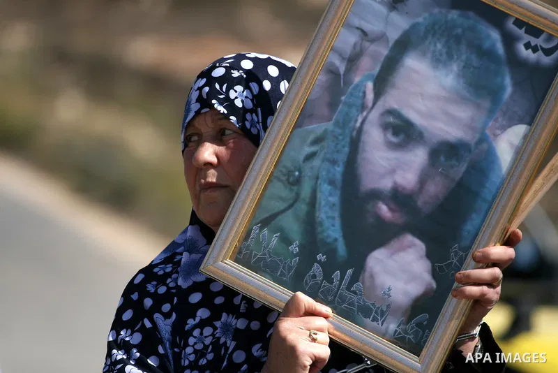 A Palestinian woman hold her jailed relative picture during a demonstration calling for the release of prisoners held in Israeli jails and in support of inmates in hunger strike, on October 5, 2011 near Israel's Ofer pri...