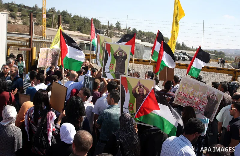 Palestinian protestors wave their national flag and shout slogans during a demonstration calling for the release of prisoners held in Israeli jails and in support of inmates in hunger strike, on October 5, 2011 near Isra...