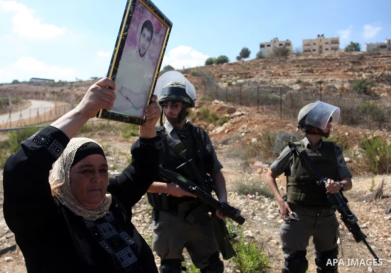 A Palestinian woman hold her jailed relative picture during a demonstration calling for the release of prisoners held in Israeli jails and in support of inmates in hunger strike, on October 5, 2011 near Israel's Ofer pri...