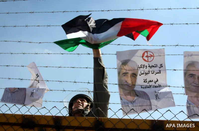 An Israeli soldier removes the Palestinian flag from the fence during a demonstration by Palestinians calling for the release of prisoners held in Israeli jails and in support of inmates in hunger strike, on October 5, 2...