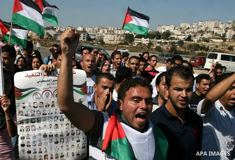 Palestinian protestors wave their national flag and shout slogans during a demonstration calling for the release of prisoners held in Israeli jails and in support of inmates in hunger strike, on October 5, 2011 near Isra...