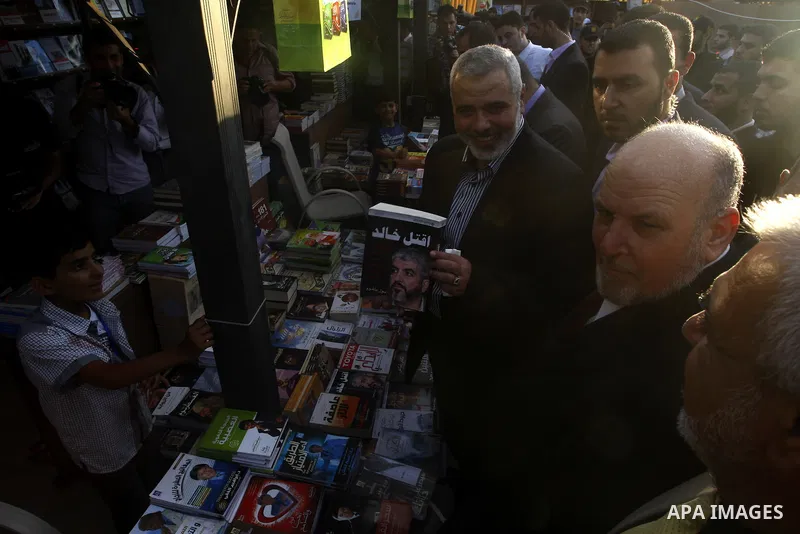 Palestinian Prime Minister in Gaza Strip, Ismail Haniya holds a book with a picture of Hamas leader Khaled Meshaal as he attends the opening ceremony of the book exhibition which organised by the Ministry of Culture in G...