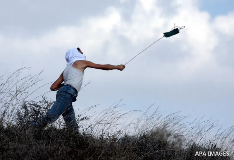 A Palestinian youth uses a sling to hurl stones towards Israeli soldiers during a weekly demonstration against Israeli settlement expansion, in the West Bank village of Nabi Saleh, on October 7, 2011. Photo by Issam Rima...