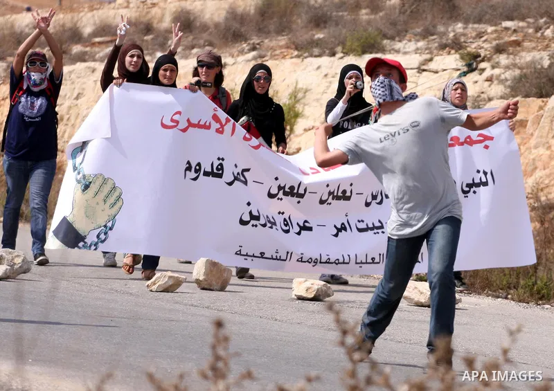 A Palestinian youth uses a sling to hurl stones towards Israeli soldiers during a weekly demonstration against Israeli settlement expansion, in the West Bank village of Nabi Saleh, on October 7, 2011. Photo by Issam Rima...