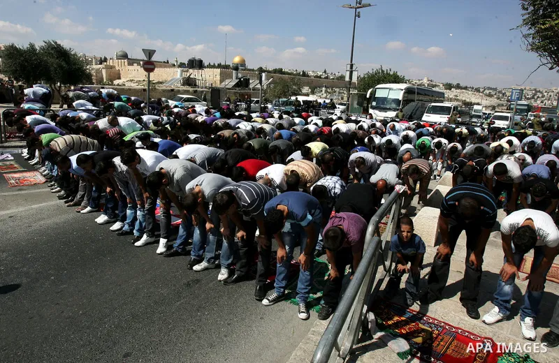 Palestinian Muslims attend Friday prayers at a street in the neighbourhood of Ras al-Amud, in East Jerusalem (Al-Aqsa Mosque compound in the background) on October 7,2011. Israel limited access to Jerusalem's Al-Aqsa mos...