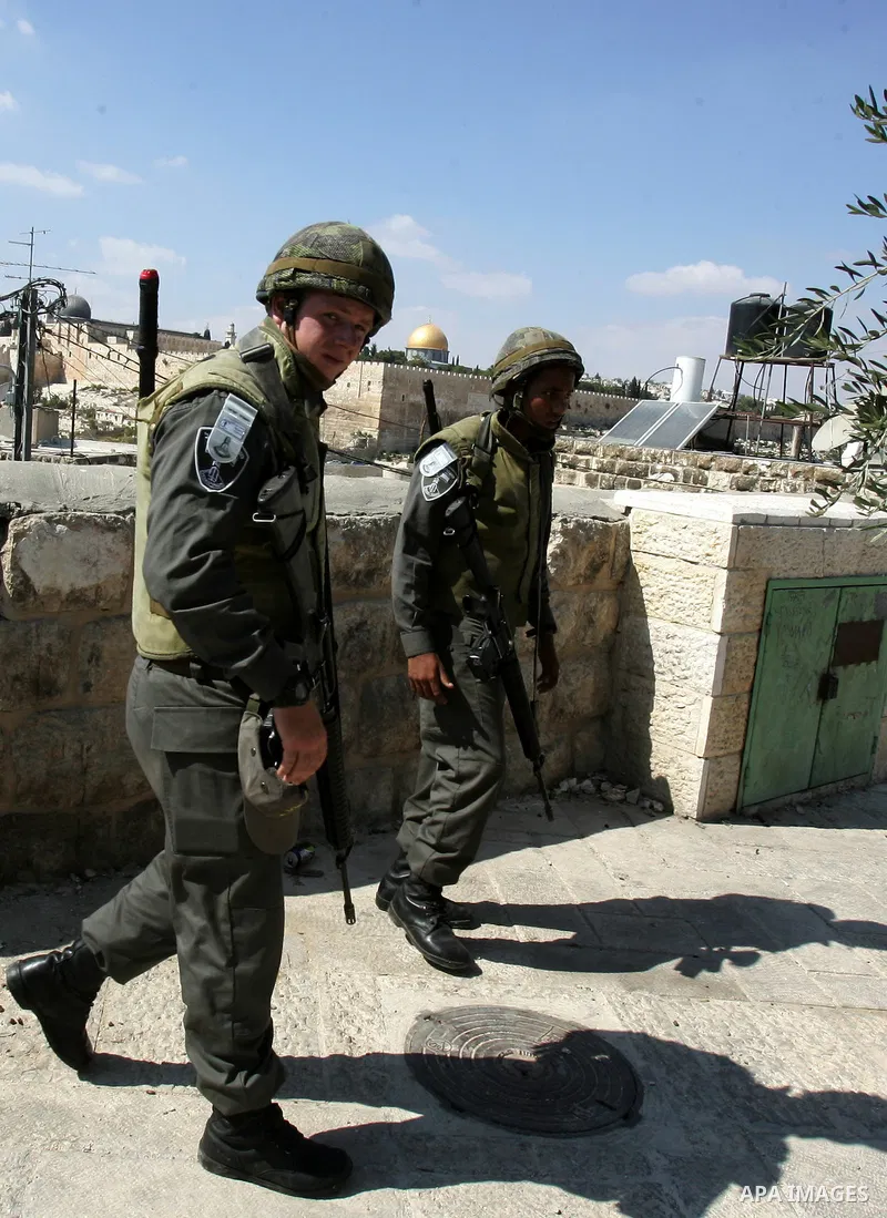 Israeli soldiers stand guard as Palestinian Muslims attend Friday prayers at a street in the neighbourhood of Ras al-Amud, in East Jerusalem (Al-Aqsa Mosque compound in the background) on October 7,2011. Israel limited a...
