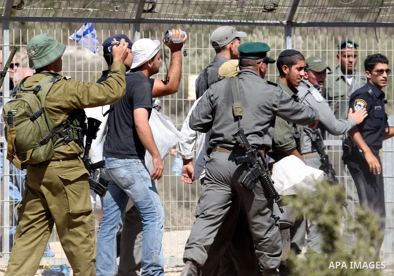 Jewish settlers from the Itamar settlement are moved along by Israeli soldiers after they clashed with Palestinian farmers from the village of Awarta in the Israeli occupied West Bank, on October 9, 2011, as they tried t...