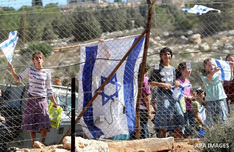 Jewish settlers from the Itamar settlement wave the Israeli flag after settlers clashed with Palestinian farmers from the village of Awarta in the Israeli occupied West Bank, on October 9, 2011, as they tried to pick oli...
