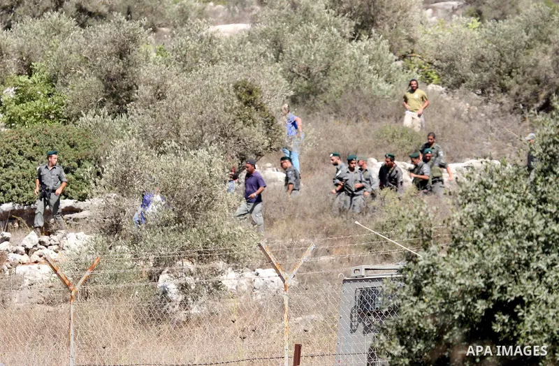 Jewish settlers from the Itamar settlement are moved along by Israeli soldiers after they clashed with Palestinian farmers from the village of Awarta in the Israeli occupied West Bank, on October 9, 2011, as they tried t...