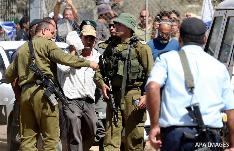 Jewish settlers from the Itamar settlement are moved along by Israeli soldiers after they clashed with Palestinian farmers from the village of Awarta in the Israeli occupied West Bank, on October 9, 2011, as they tried t...