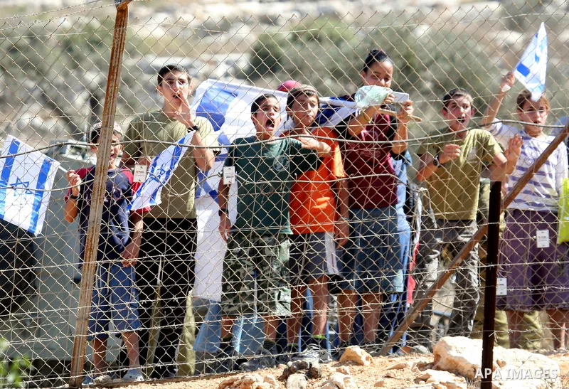 Jewish settlers from the Itamar settlement wave the Israeli flag after settlers clashed with Palestinian farmers from the village of Awarta in the Israeli occupied West Bank, on October 9, 2011, as they tried to pick oli...