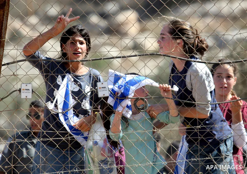 Jewish settlers from the Itamar settlement wave the Israeli flag after settlers clashed with Palestinian farmers from the village of Awarta in the Israeli occupied West Bank, on October 9, 2011, as they tried to pick oli...