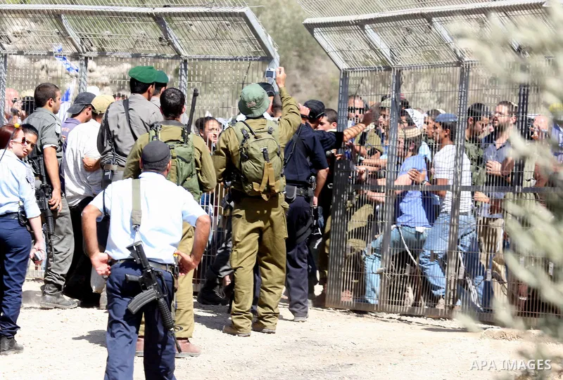 Jewish settlers from the Itamar settlement are moved along by Israeli soldiers after they clashed with Palestinian farmers from the village of Awarta in the Israeli occupied West Bank, on October 9, 2011, as they tried t...