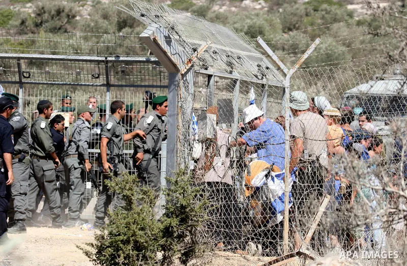 Jewish settlers from the Itamar settlement are moved along by Israeli soldiers after they clashed with Palestinian farmers from the village of Awarta in the Israeli occupied West Bank, on October 9, 2011, as they tried t...