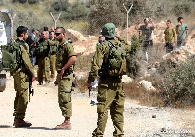 Jewish settlers from the Itamar settlement are moved along by Israeli soldiers after they clashed with Palestinian farmers from the village of Awarta in the Israeli occupied West Bank, on October 9, 2011, as they tried t...