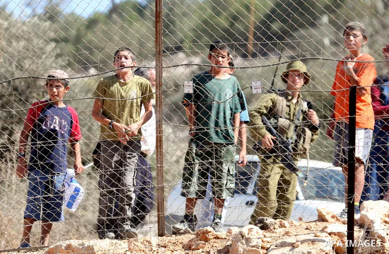 Jewish settlers from the Itamar settlement are moved along by Israeli soldiers after they clashed with Palestinian farmers from the village of Awarta in the Israeli occupied West Bank, on October 9, 2011, as they tried t...