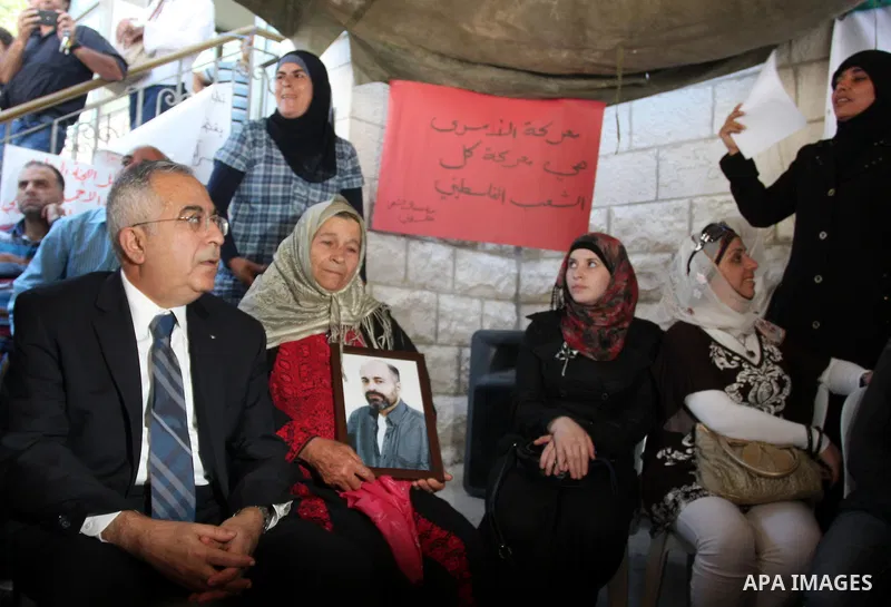 Palestinian prime minister Salam Fayyad sits with relatives of Palestinian prisoners who are held in Israeli jails in a protest tent build in front of the Red Cross' offices in the West Bank city of Ramallah, on October...
