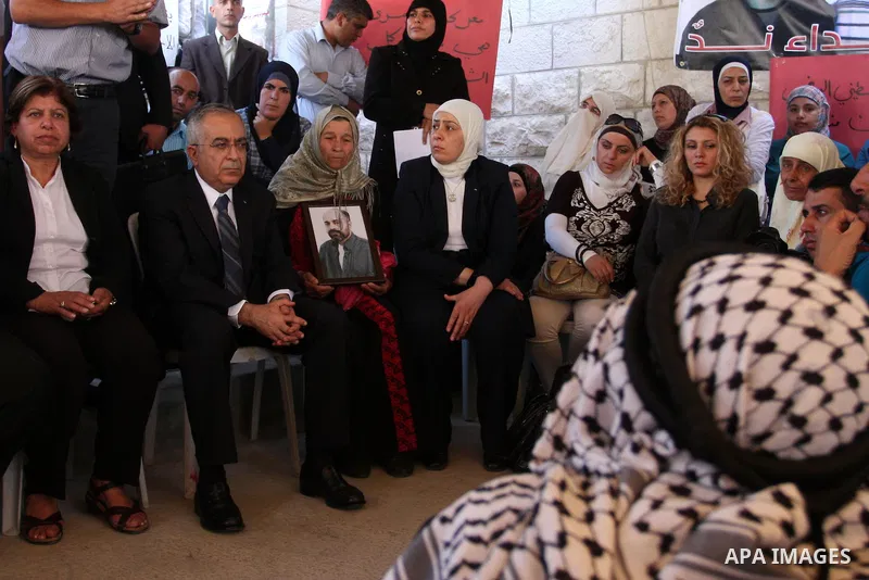 Palestinian prime minister Salam Fayyad sits with relatives of Palestinian prisoners who are held in Israeli jails in a protest tent build in front of the Red Cross' offices in the West Bank city of Ramallah, on October...