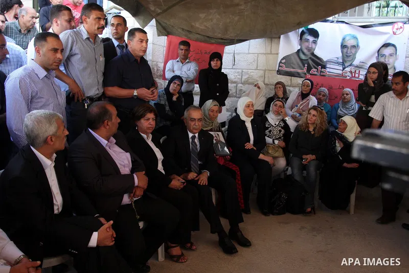 Palestinian prime minister Salam Fayyad sits with relatives of Palestinian prisoners who are held in Israeli jails in a protest tent build in front of the Red Cross' offices in the West Bank city of Ramallah, on October...