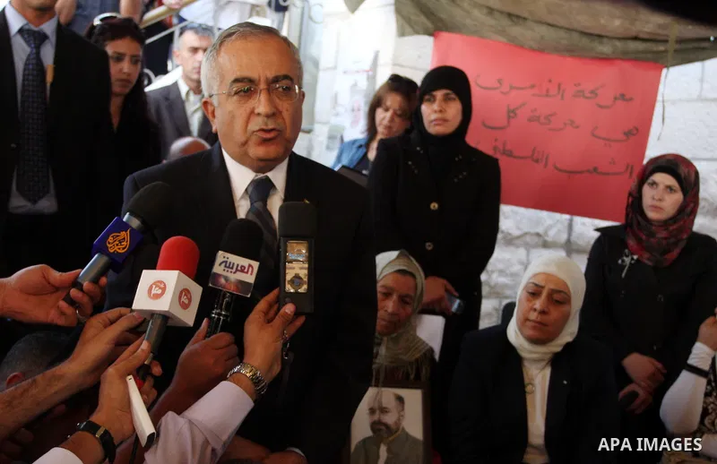 Palestinian prime minister Salam Fayyad sits with relatives of Palestinian prisoners who are held in Israeli jails in a protest tent build in front of the Red Cross' offices in the West Bank city of Ramallah, on October...