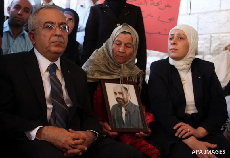 Palestinian prime minister Salam Fayyad sits with relatives of Palestinian prisoners who are held in Israeli jails in a protest tent build in front of the Red Cross' offices in the West Bank city of Ramallah, on October...
