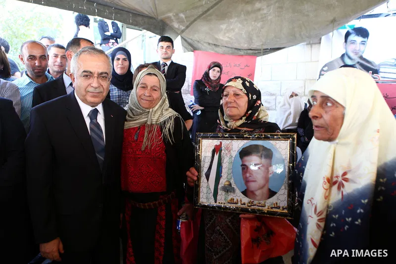 Palestinian prime minister Salam Fayyad sits with relatives of Palestinian prisoners who are held in Israeli jails in a protest tent build in front of the Red Cross' offices in the West Bank city of Ramallah, on October...