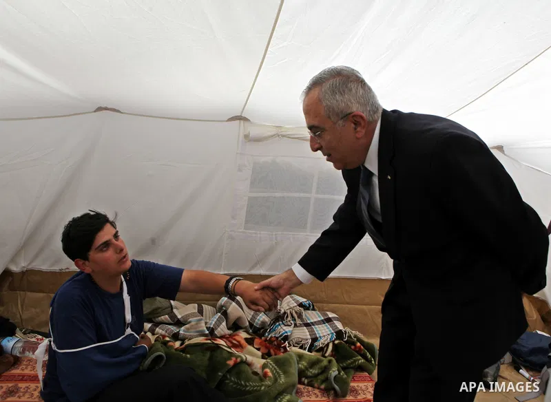 Palestinian prime minister Salam Fayyad sits with relatives of Palestinian prisoners who are held in Israeli jails in a protest tent build in front of the Red Cross' offices in the West Bank city of Ramallah, on October...