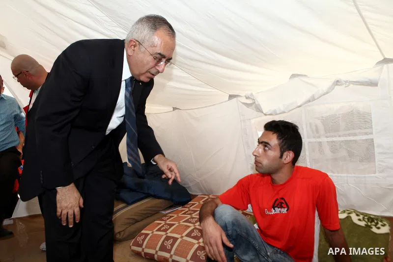 Palestinian prime minister Salam Fayyad sits with relatives of Palestinian prisoners who are held in Israeli jails in a protest tent build in front of the Red Cross' offices in the West Bank city of Ramallah, on October...