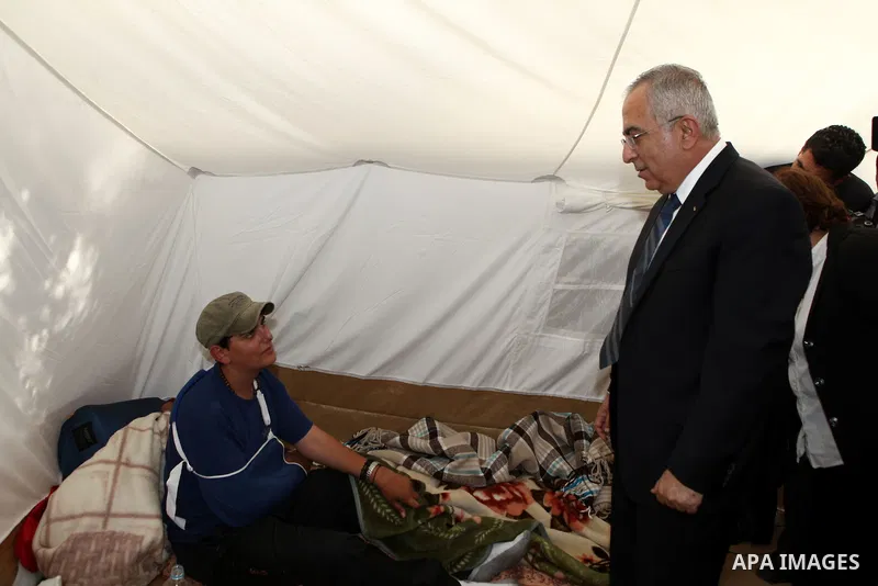 Palestinian prime minister Salam Fayyad sits with relatives of Palestinian prisoners who are held in Israeli jails in a protest tent build in front of the Red Cross' offices in the West Bank city of Ramallah, on October...