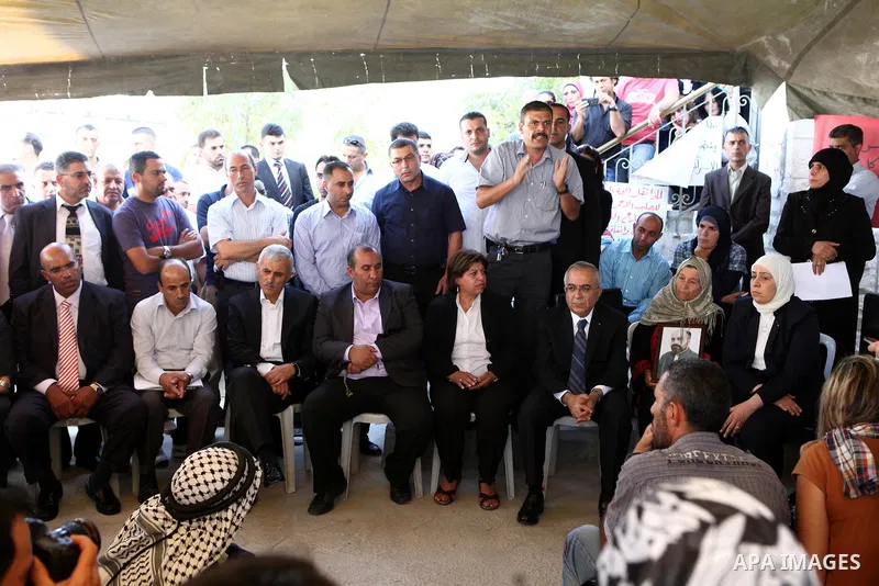 Palestinian prime minister Salam Fayyad sits with relatives of Palestinian prisoners who are held in Israeli jails in a protest tent build in front of the Red Cross' offices in the West Bank city of Ramallah, on October...