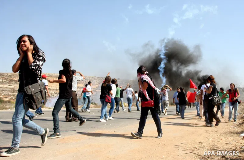 Palestinian protestors run for cover as Israeli forces fire tear gas canisters during clashes following a demonstration calling for the release of prisoners held in Israeli jails and in support of inmates in hunger strik...