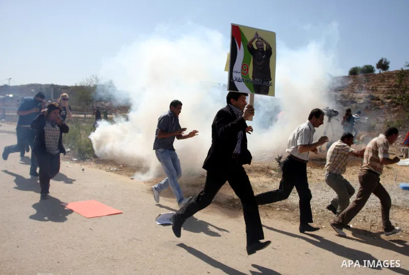 Palestinian protestors run for cover as Israeli forces fire tear gas canisters during clashes following a demonstration calling for the release of prisoners held in Israeli jails and in support of inmates in hunger strik...