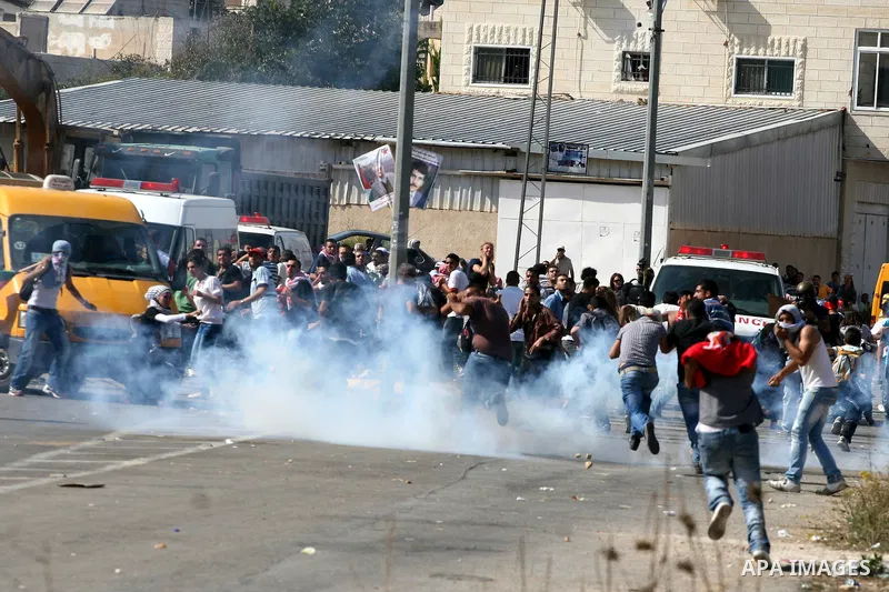 Palestinian protestors run for cover as Israeli forces fire tear gas canisters during clashes following a demonstration calling for the release of prisoners held in Israeli jails and in support of inmates in hunger strik...