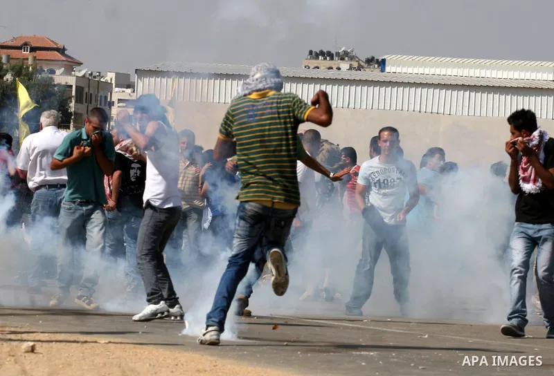 Palestinian protestors run for cover as Israeli forces fire tear gas canisters during clashes following a demonstration calling for the release of prisoners held in Israeli jails and in support of inmates in hunger strik...