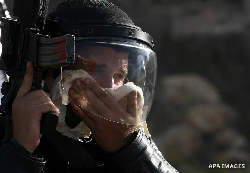 An Israeli soldier reacts to tear gas fired at Palestinians during a demonstration calling for the release of prisoners held in Israeli jails and in support of inmates in hunger strike, on October 11, 2011 near Israel's...