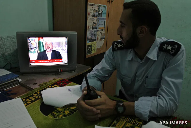 Palestinian Hamas security forces watch a television broadcasting the speech of Hamas leader Khaled Meshaal celebrating a deal that will see Palestinian detainees freed in exchange for Israeli soldier Gilad Shalit on Oct...