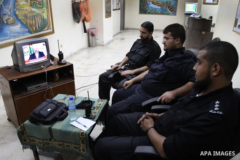 Palestinian Hamas security forces watch a television broadcasting the speech of Hamas leader Khaled Meshaal celebrating a deal that will see Palestinian detainees freed in exchange for Israeli soldier Gilad Shalit on Oct...