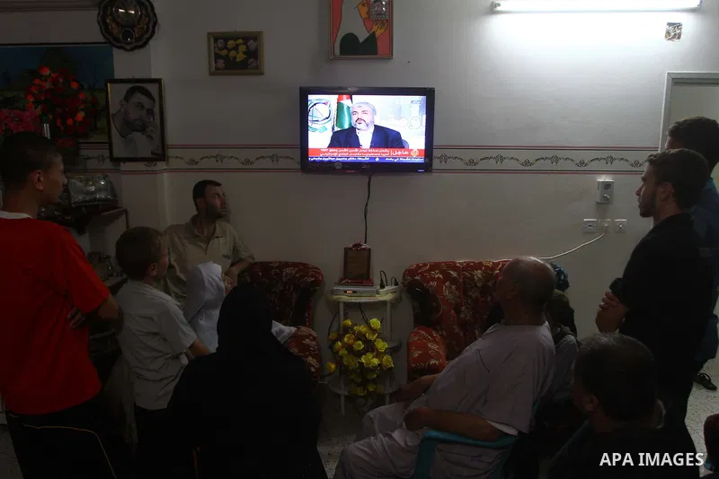 The Family of Mohammed al-Falet, watch a television broadcasting the speech of Hamas leader Khaled Meshaal, celebrating a deal that will see Palestinian detainees freed in exchange for Israeli soldier Gilad Shalit, Moham...