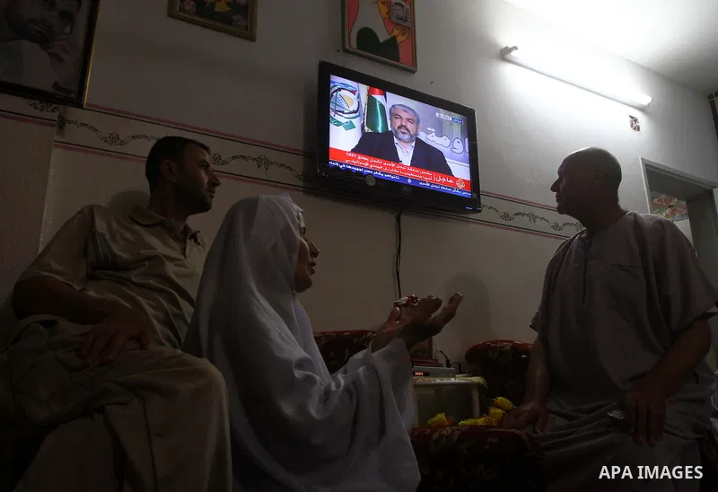 The Family of Mohammed al-Falet, watch a television broadcasting the speech of Hamas leader Khaled Meshaal, celebrating a deal that will see Palestinian detainees freed in exchange for Israeli soldier Gilad Shalit, Moham...