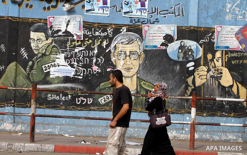 Palestinians walk in front of a wall painting depicting Israeli soldier Gilad Schalit, who is being held in Gaza since he was captured by Hamas-allied militants in a cross-border raid in 2006, in Jebaliya, northern Gaza...