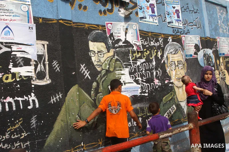Palestinians walk in front of a wall painting depicting Israeli soldier Gilad Schalit, who is being held in Gaza since he was captured by Hamas-allied militants in a cross-border raid in 2006, in Jebaliya, northern Gaza...