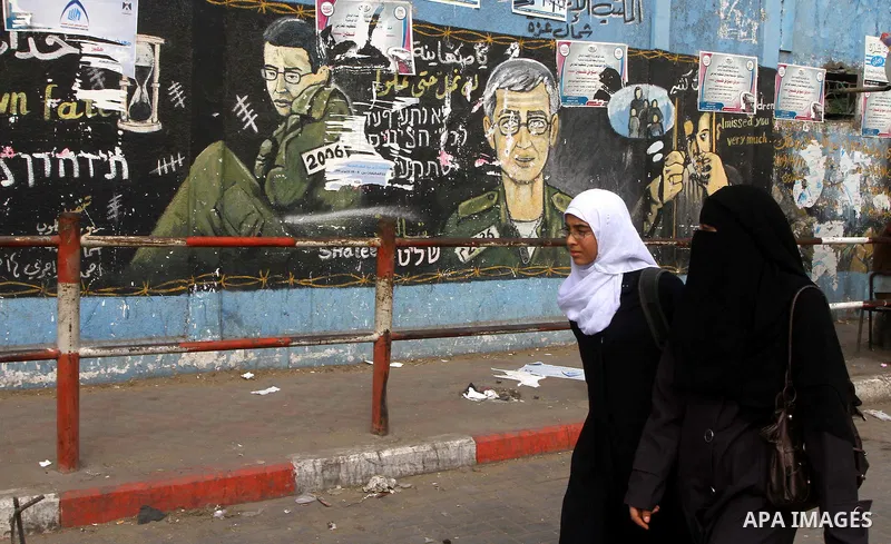 Palestinians walk in front of a wall painting depicting Israeli soldier Gilad Schalit, who is being held in Gaza since he was captured by Hamas-allied militants in a cross-border raid in 2006, in Jebaliya, northern Gaza...