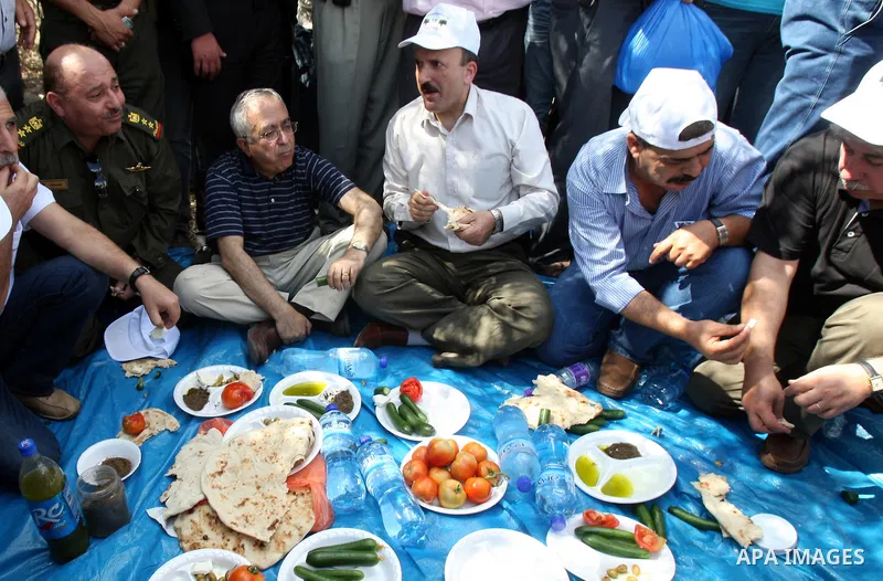 Palestinian Prime Minister Salam Fayyad eat with Palestinian farmers during his visit at the beginning of olive harvest season in the West Bank village of Feraon, near Tulkarem, Thursday, Oct. 13, 2011. A Hamas official...