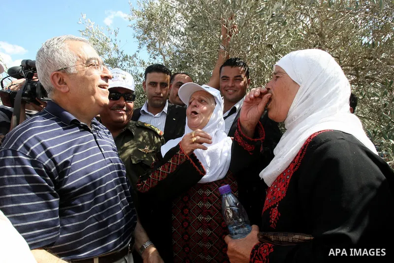 Palestinian Prime Minister Salam Fayyad speaks with Palestinian farmers during his visit at the beginning of olive harvest season in the West Bank village of Feraon, near Tulkarem, Thursday, Oct. 13, 2011. A Hamas offici...