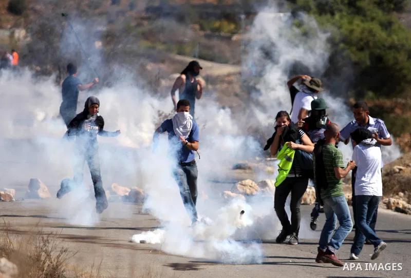 Palestinian, Israeli and foreign activists run away from tear gas canisters fired by Israeli troops during a demonstration against the expansion of the nearby Jewish settlement of Halamish in the West Bank village of Nab...